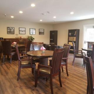 A cozy dining room with wooden tables and chairs, decorated with wall art and illuminated by ceiling lights.