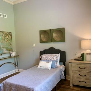 A minimalist bedroom with a single bed, nightstand, and contemporary artwork.