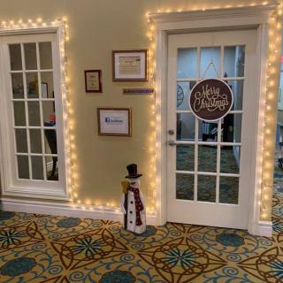 A festive hallway featuring glass doors adorned with string lights and a snowman decoration.