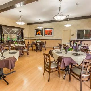 A well-organized dining area with multiple tables and chairs, adorned with elegant decor and ambient lighting.