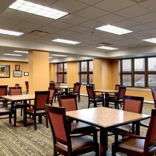 An empty dining area with neatly arranged tables and chairs, lit by overhead lighting.