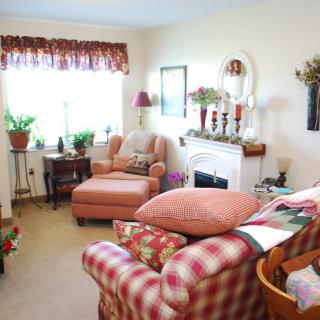 A cozy living room with colorful furniture and a variety of decorations, including plants and a fireplace.