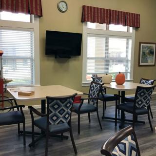 A cozy dining area with tables, chairs, and a wall-mounted television.