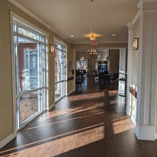 A sunlit hallway with large windows and elegant chandeliers.