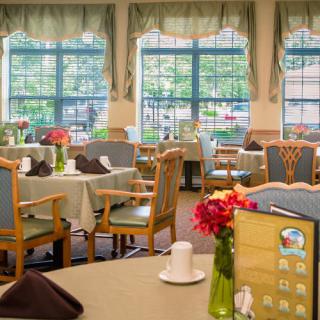 A cozy dining area with elegantly set tables and large windows.