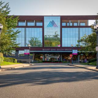 A modern commercial building with a glass facade and landscaped surroundings.
