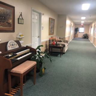 A well-lit hallway with a piano and seating area.