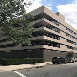 A modern multi-level building with a parking area in an urban setting.