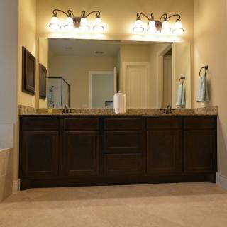A spacious bathroom featuring a large mirror, double sink vanity, and elegant lighting fixtures.