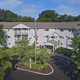 Aerial view of a residential apartment building surrounded by lush trees and landscaping.