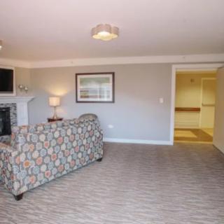 A cozy living room with a patterned sofa, fireplace, and carpeted flooring.