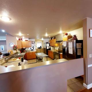 A modern kitchen featuring wooden cabinets, countertops, and various appliances under warm lighting.