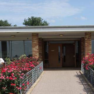 The entrance of a modern building framed by vibrant flowers.