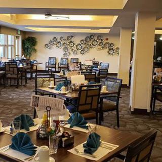 A well-arranged dining area with neatly set tables, featuring blue napkins and an artistic wall decoration.