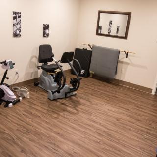 A home gym with a stationary bike and exercise equipment on a wooden floor.