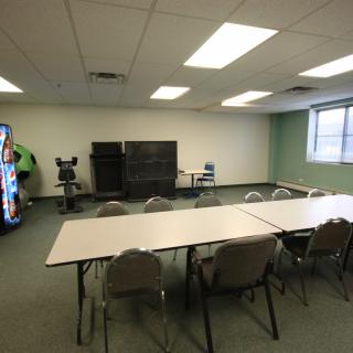 A simple meeting room equipped with a long conference table, chairs, a vending machine, and televisions.