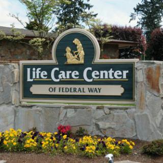 Sign for Life Care Center of Federal Way surrounded by flowers and trees.