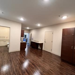 Spacious room with wooden floors and modern kitchen area.