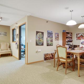 A cozy dining room with a wooden table, chairs, and decorative art on the walls.