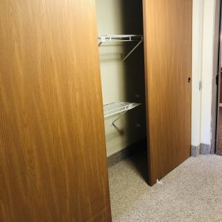 An empty closet with wooden sliding doors and a carpeted floor.