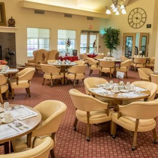 An elegant dining room with neatly arranged tables and chairs, featuring large windows and stylish decor.