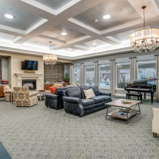 A spacious and elegantly designed living room with comfortable seating, a fireplace, and a piano.