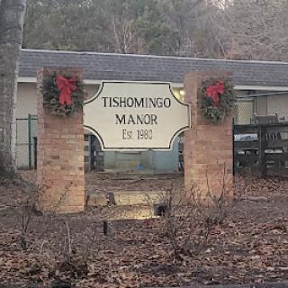 Entrance sign of Fishmonger's Manor adorned with holiday wreaths.