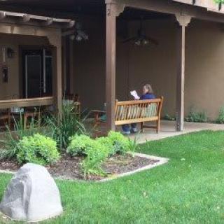 A person reading on a bench in a garden patio area.