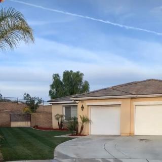 A suburban house with a double garage and well-maintained landscaping under a clear blue sky.