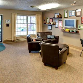 A cozy waiting room with leather chairs, a television, and framed certificates on the wall.