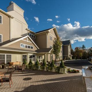 A sunny outdoor view of a modern building with a patio area.