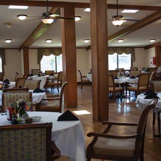 A spacious dining area with tables and chairs set up, illuminated by natural light.