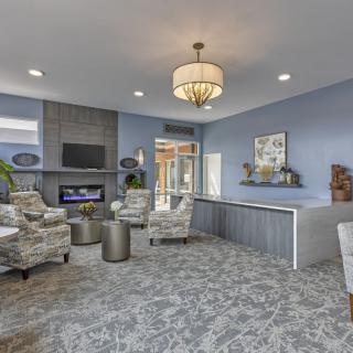 A modern living room with a stylish chandelier, comfortable seating, and a fireplace beneath a mounted television.