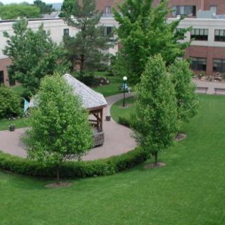 A peaceful garden area featuring a gazebo surrounded by lush greenery and neatly trimmed lawns.