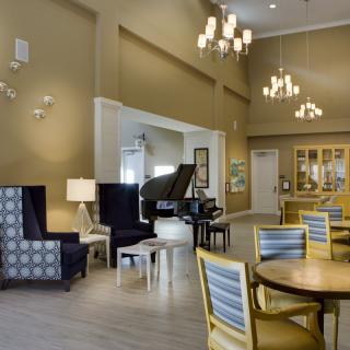 A stylish lounge area featuring comfortable seating, elegant chandeliers, and a grand piano.
