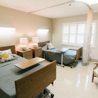 A clean and bright hospital room with two beds and a curtain divider.