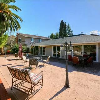 A spacious backyard patio with outdoor furniture and a palm tree under a clear, sunny sky.