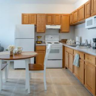 A cozy kitchen with wooden cabinets, equipped with essential appliances and a small dining area.