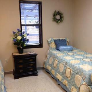 A cozy bedroom with twin beds adorned in patterned bedding, featuring a nightstand with a floral arrangement.