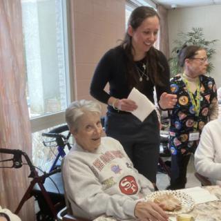 A group of people gathered around a dining table in a care home setting.