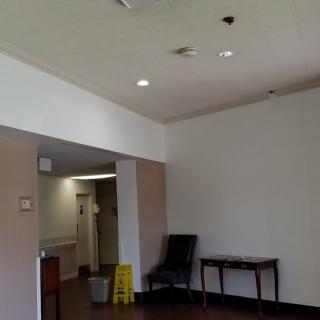 A lobby area with a chair, table, and caution sign.