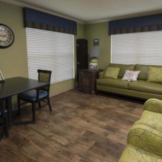 A cozy living room with a green sofa, wooden floors, and a small dining area.