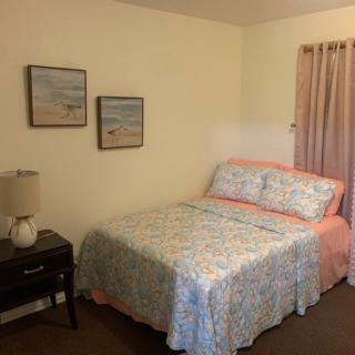 A cozy bedroom with a neatly made bed, decorative artwork, and a nightstand with a lamp.