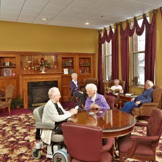 A group of elderly people socializing in a retirement home's common area.