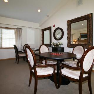 A well-furnished dining room featuring a round table with chairs, large mirrors on the walls, and elegant decor.
