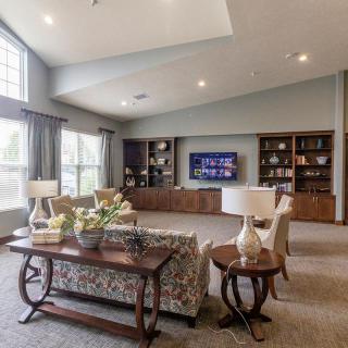A spacious living room with large windows, comfortable seating, and built-in bookshelves featuring a modern TV setup.