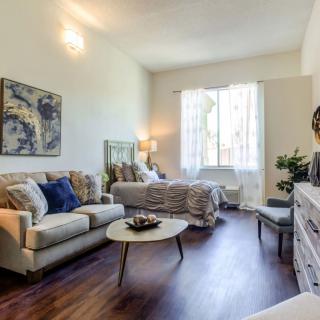 A cozy, well-lit living room with a sofa and coffee table, blending seamlessly into a bedroom area.