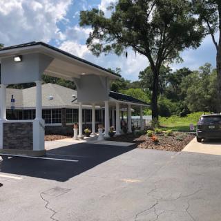 A building with a drive-thru on a sunny day surrounded by trees.