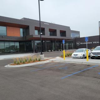 A view of a modern building with a parking lot in front.