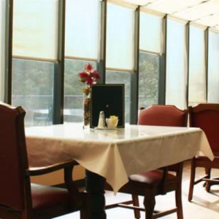 A sunlit dining area with a neatly set table and chairs by the window.